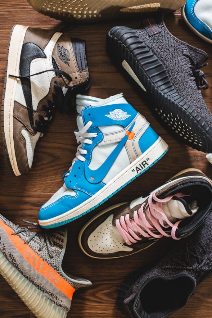 Multicolor trendy sneakers of different pairs of footwear lying on wooden surface discordantly